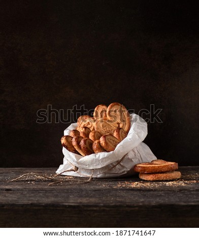 French Palmier cookies in a paper bag on a dark background with space for text.
