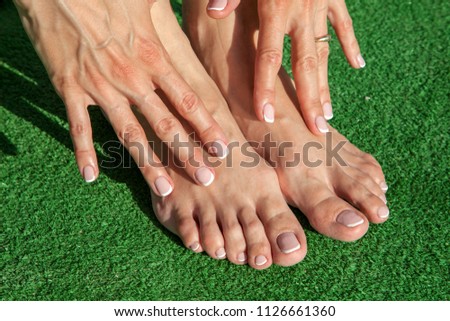 French pedicure with manicure on a girl on green grass