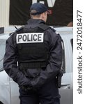 a french policeman seen from behind during an intervention