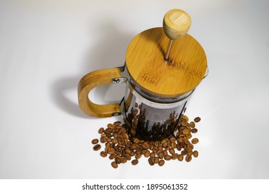 French Press Coffee Maker On The White Ground. Arabic Coffee Beans Bottom Of The French Press And Cooked Caffe Inside The Glass Side Of The Press And Wooded Details.