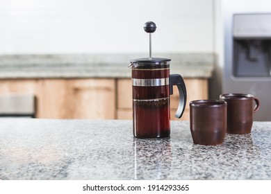 French Press With Fresh Coffee Next To Two Mugs On A Modern Kitchen Counter. No People In The Making. Selective Focus