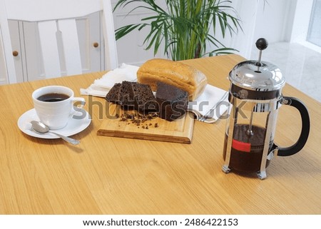French press with tea cup and bread on the table