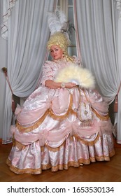 French queen Marie Antoinette wears pink dress in palace interior. Full height portrait of woman in reconstructed historical medieval royal costume of 18th century