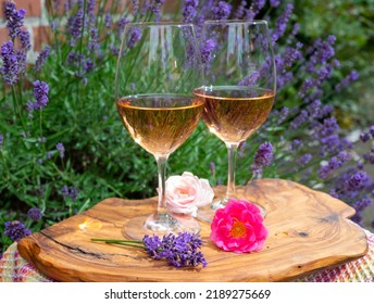 French Rose Wine From Provence, Two Glasses Of Wine With Purple Lavender Flowers On Background Served On Olive Tree Plank Outdoor In Sunny Day