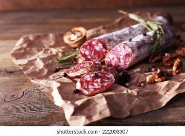 French salami and walnuts on craft paper on wooden background