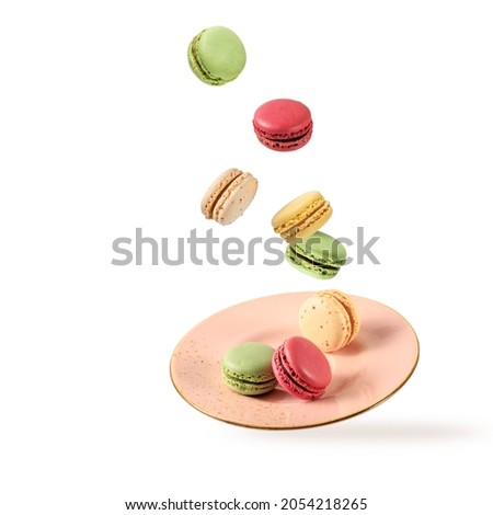 French sweet colorful cookies macarons macaroons flying falling on vintage pink plate isolated  on white background. Pastry shop card with copy space
