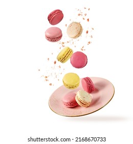 French Sweet Colorful Fruit Cookies Macarons Macaroons With Crumbs Flying Falling On Vintage Pink Plate Isolated  On White Background. Pastry Shop Card With Copy Space