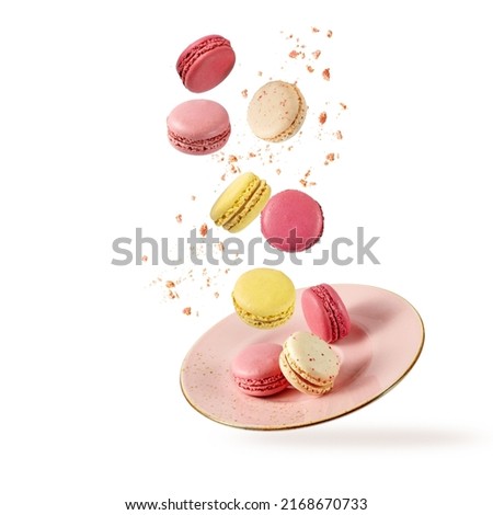 French sweet colorful fruit cookies macarons macaroons with crumbs flying falling on vintage pink plate isolated  on white background. Pastry shop card with copy space