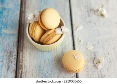 French sweet yellow cookies macarons macaroons in a pastel yellow bowl on wooden blue background. Pastry shop card with copy space. Traditional french macaroons with white flowers, spring blossom - Powered by Shutterstock