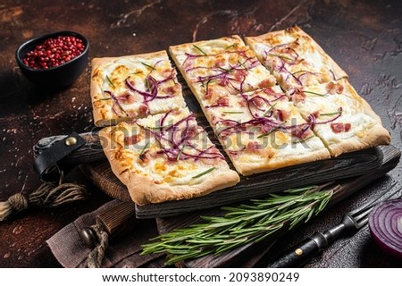 French tarte flambee with cream cheese, bacon and onions. Flammkuchen from Alsace region. Dark background. Top view