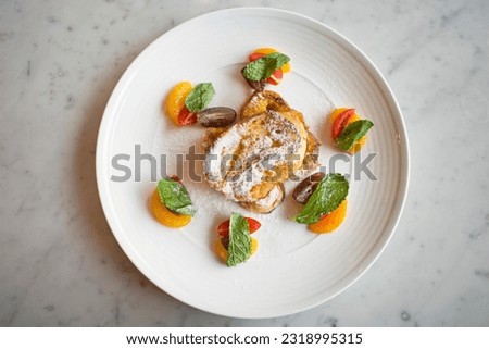 French toast with maple syrap, rasp berry sauce and fruits on a white plate.