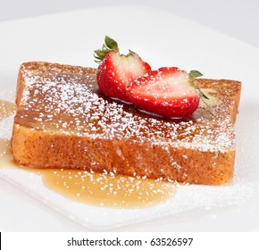 French Toast With Powdered Sugar And A Strawberry On White