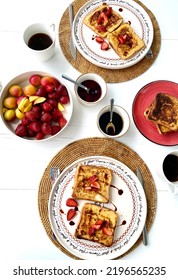 French Toast With Strawberries And Maple Syrup On A Straw Service. A Side Of Jams, A Fruit Plate With Peaches And Strawberries, Breakfast With Coffee. Focused And Overhead Shooting.