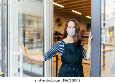 French Woman In Protective Mask Open Door Of The Shop For Welcome The Customer In To The Coffee Shop, Small Business Owner And Startup With Cafe Shop, Installing Open And Close Concept