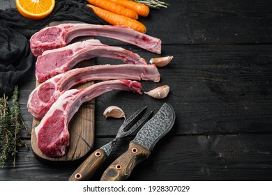 Frenched raw fatty lamb chops set, with ingredients carrot orange, herbs, on black wooden table background , with copyspace and space for text - Shutterstock ID 1928307029