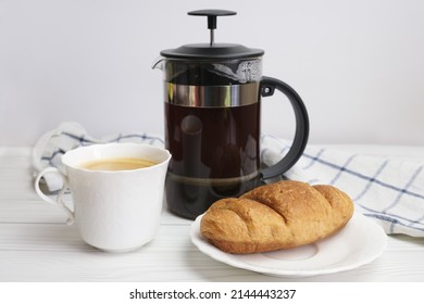 French-pressed ground coffee and a white porcelain cup and saucer. Preparing ground coffee in a press. Refreshing drink for breakfast. - Powered by Shutterstock