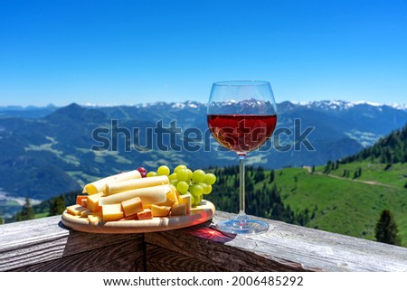 fresch tirol cheese with wine and grapes over mountain landscape .
