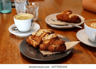 Fresh almond croissant paired with a cup of coffee, served on a café table - Powered by Shutterstock