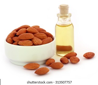 Fresh almonds with bottle of oil over white background