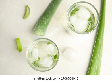 Fresh aloe drink in glasses and leaves on light table, flat lay