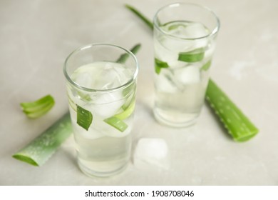 Fresh aloe drink in glasses and leaves on light table