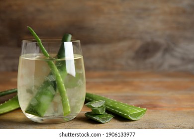 Fresh aloe drink with leaves in glass on wooden table. Space for text