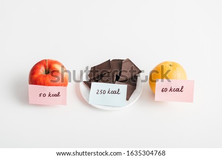 Fresh apple, orange and chocolate with calories on cards on white background, calorie counting diet