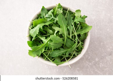 Fresh Arugula Salad On A Grey Stone Background.