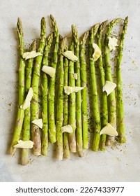 Fresh asparagus with oil, butter and spices, stemed of grilling, on white paper, top view