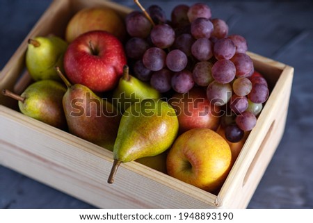 fresh assorted fruits in a wooden box, pears, apples, grapes, close-up