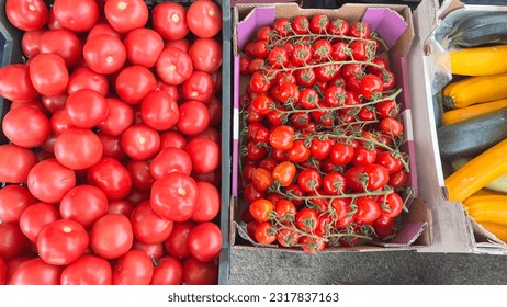 Fresh assorted vegetables in a plastic crate. Ripe red tomatoes, in plastic boxes on the counter of the outside store. Vegetables, farmers market