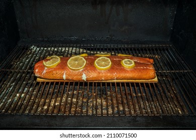 Fresh Atlantic Salmon On A Cedar Plank With Lemon Slices On A Pellet Smoker