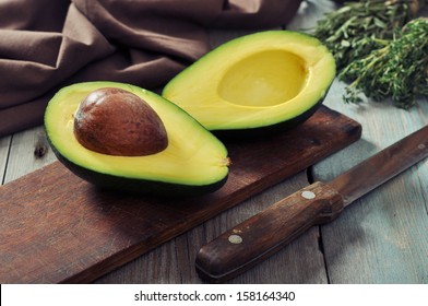 Fresh avocado on cutting board over wooden background