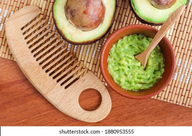 Fresh Avocado Puree In A Small Bowl And Wooden Hairbrush. Homemade Face Or Hair Mask, Natural Beauty Treatment And Spa Recipe. Top View, Copy Space. 