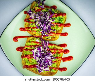 Fresh Avocado Toast Served With Sriracha And Purple Cabbage