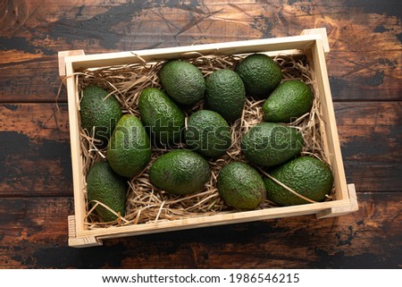 Fresh avocado in wooden box on rustic table