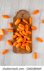 Fresh Baby Carrots On Rustic Wooden Board On A White Wooden Background, Top View. Overhead, From Above, Flat Lay. 