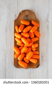 Fresh Baby Carrots On Rustic Wooden Board On A White Wooden Background, Top View. Overhead, From Above, Flat Lay. Close-up.