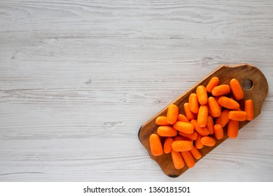 Fresh Baby Carrots On Rustic Wooden Board On A White Wooden Surface, Top View. Overhead, From Above, Flat Lay. Copy Space.