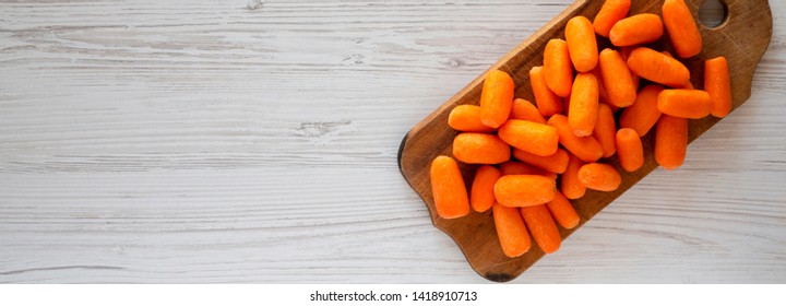 Fresh Baby Carrots On A Rustic Wooden Board On A White Wooden Background, Top View. Overhead, From Above, Flat Lay. Copy Space.