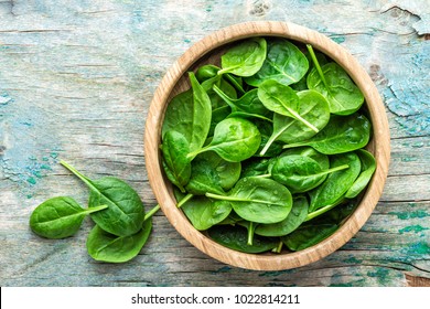 Fresh baby spinach leaves in bowl on wooden background - Shutterstock ID 1022814211