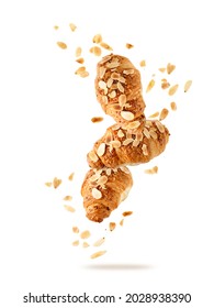 Fresh baked almond  breakfast croissants  with nuts flakes crumbs flying isolated on white background. Three croissants falling. Pastry shop card.