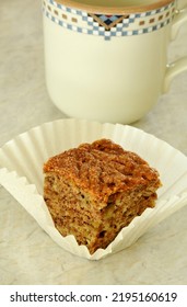 Fresh Baked Banana Bread Square With Raisins And Cinnamon Sugar Topping. In Parchment Cupcake Liner With Mug In Vertical Format.
