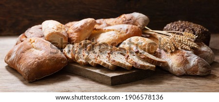 Fresh baked bread and wheat ears on a wooden background