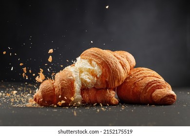 Fresh Baked Breakfast Croissants With Crumbs Flying Isolated On Black Background