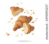 Fresh baked butter breakfast croissants and crumbs falling flying isolated on white background. Whole and broken in half croissants. Pastry shop or bakery card.