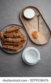 Fresh baked cookies biscotti on a grey  round plate with a cup and creamy sauce on a tray.