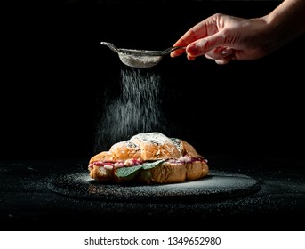 Fresh Baked Croissants With Falling Powdered Sugar On Dark Background