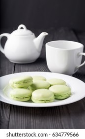 Fresh baked green macaroon pastry cookies on a white plate with cup and kettle. - Shutterstock ID 634779566
