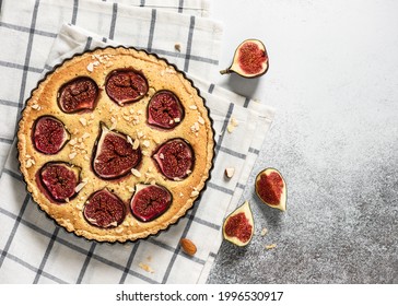 Fresh baked homemade delicious tart with figs, almond nuts and honey in baking pan on checkered kitchen towel. Flat lay. Copy space.